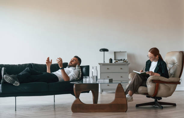 istock Man is lying down on the sofa, session with woman psychologist 1832574670