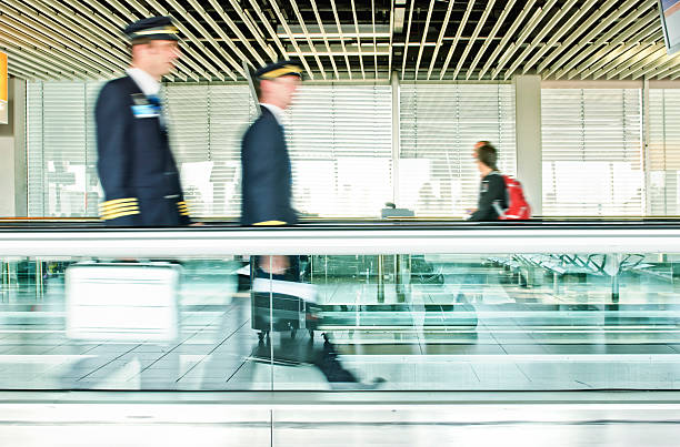 airplane pilots blurred motion of two airplane pilots on a Moving Walkway airport travelator stock pictures, royalty-free photos & images