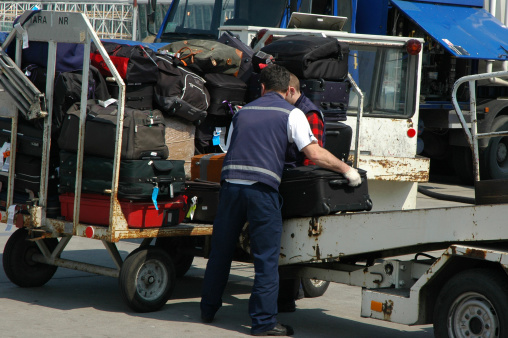Luggage is off-loaded from an aircraft by groundstaff.
