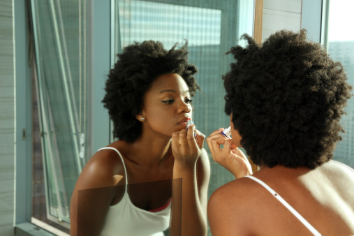 African American aplicándose el lápiz labial en un espejo photo