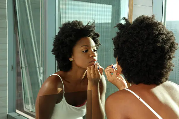 Photo of African American Woman Putting on Lipstick in a Mirror
