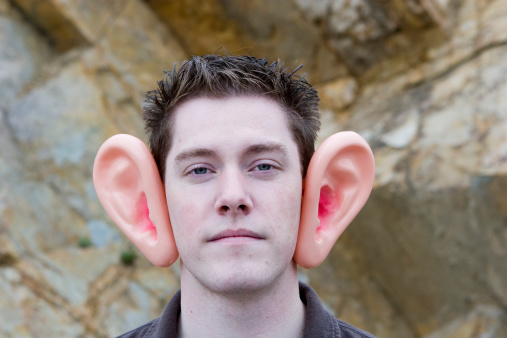 A serious young man wearing big ears to emphasize the importance of listening and communication.