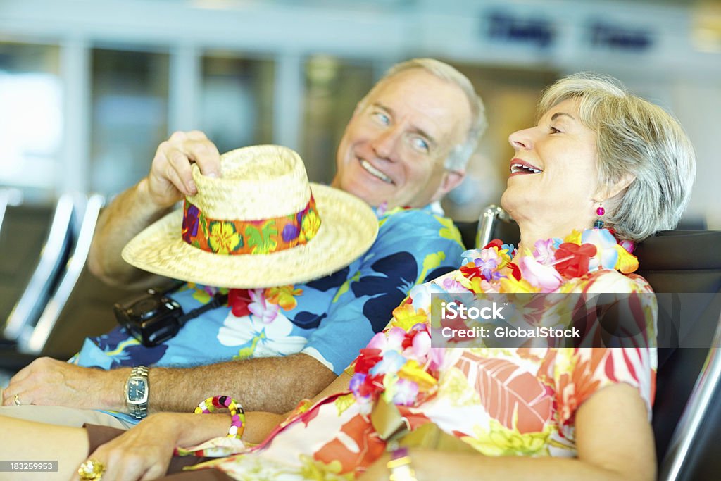 Casal sênior em roupas de flores esperando em um lounge de aeroporto - Foto de stock de Aeroporto royalty-free