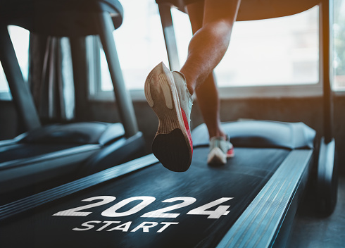 Happy new year 2024,2024 symbolizes the start of the new year. Close up of feet, sportsman runner running on treadmill in fitness club. Cardio workout. Healthy lifestyle, guy training in gym.