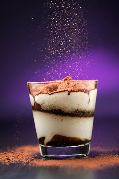 Pouring cacao powder to tiramisu in glass Pouring cacao powder to tiramisu in glass tiramisu glass stock pictures, royalty-free photos & images