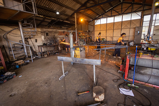A team of skilled women in a metal workshop, expertly welding together a sturdy metal structure.