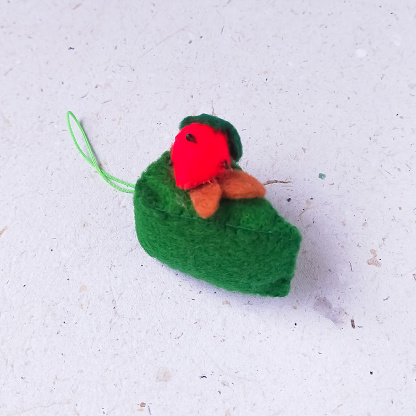 Handmade mini cake made of felt and woolen toys on a white background as phone strap