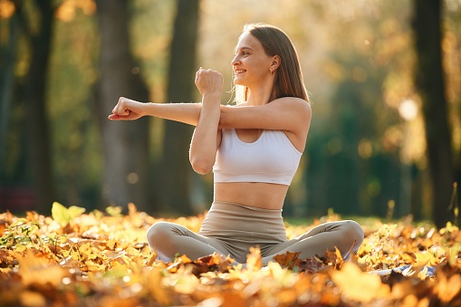 Hands exercises. Young beautiful woman is doing yoga in the autumn park.