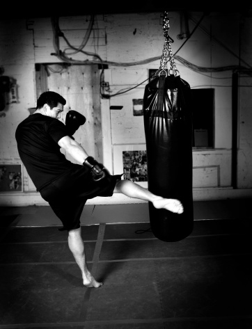 Man kicking heavy bag in gym. Black and white. Please see some similar pictures from my portfolio: