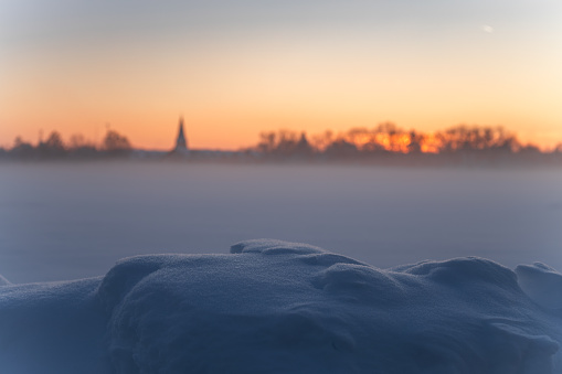 cold winter snow meadow covered in ice and foggy landscape at sunset