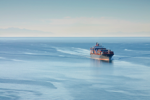 Distant aerial photo of a loaded container ship at sea.