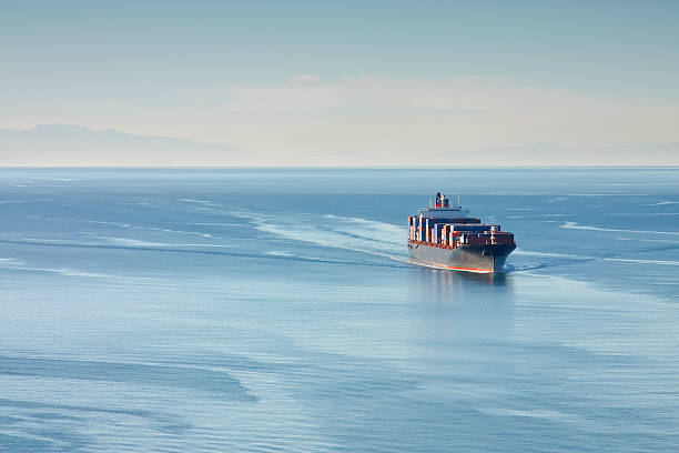 Container Ship Distant aerial photo of a loaded container ship at sea. maritime container stock pictures, royalty-free photos & images