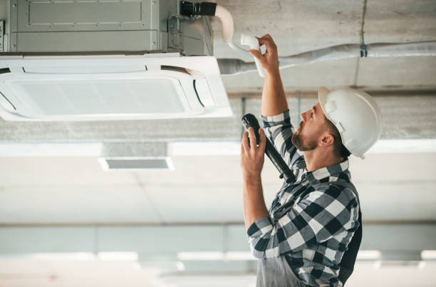 istock Ventilation system high up on the ceiling, fixing. Repairman in uniform is in the unfinished building 1832648806