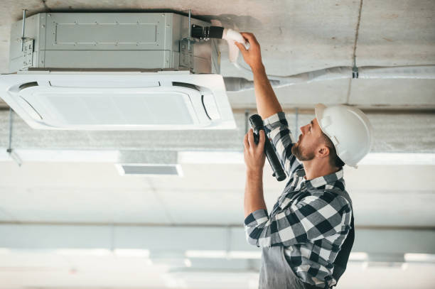istock Ventilation system high up on the ceiling, fixing. Repairman in uniform is in the unfinished building 1832648816