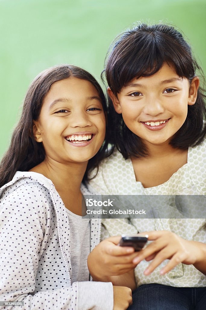 Dwa szczęśliwy Młody dziewczyny w szkole telefon komórkowy - Zbiór zdjęć royalty-free (Brązowe włosy)