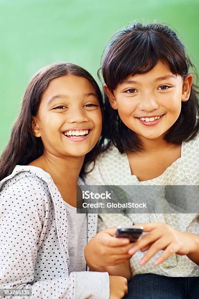 Foto de Duas Meninas Da Escola Jovem Feliz Com Um Aparelho Semelhante A Um Celular e mais fotos de stock de Alegria