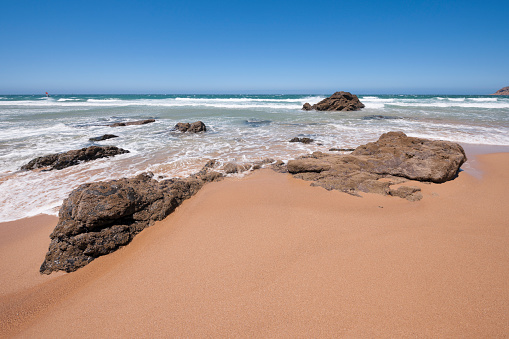 Clear blue sky, steep cliffs and the Atlantic Ocean viewed from a spot near Guincho Beach, Cascais and Lisbon in Portugal on a sunny day in summer. The image was captured with a full frame DSLR camera and a sharp lens at low ISO.