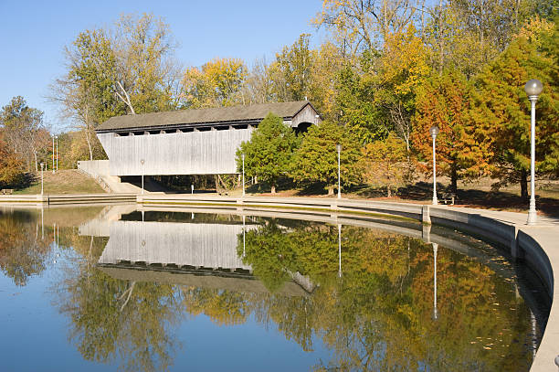 Brownsville Covered Bridge Reflection "The Brownsville Covered Bridge, located in Mill Race Park in Columbus, Indiana, was originally moved from Union County, Indiana to Eagle Creek, where it was put into storage until its rejuvenation at Mill Race Park.  It is considered the longest single lane covered bridge in Indiana." indiana covered bridge stock pictures, royalty-free photos & images