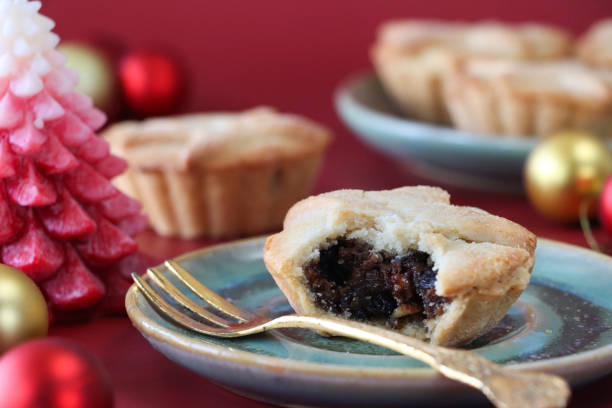istock Full frame image of mince pie with missing bite on green plate with gold fork, red wax Christmas tree candle, gold and red baubles, red background, focus on foreground 1832667275