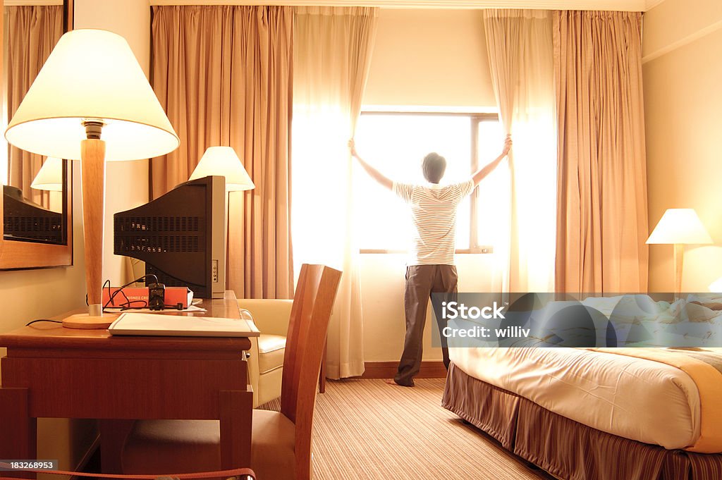 Hotel Room A man moving the curtain to have an outside view from the hotel room. Adult Stock Photo