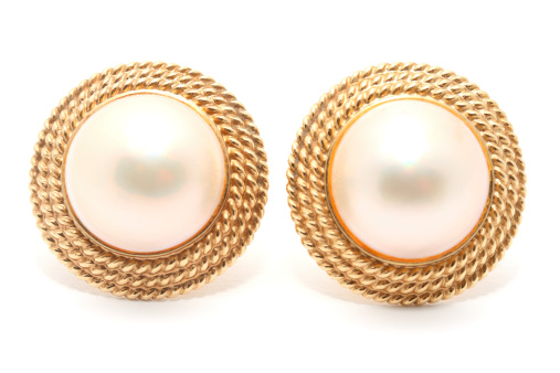 Pair of round pearl earrings on white background