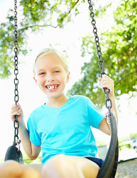 istock Smiling young girl sitting on swing at park 183269319