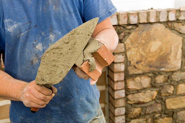 stone mason buttering ziegel mit stößel für neue kamin genießen - mason brick bricklayer installing stock-fotos und bilder