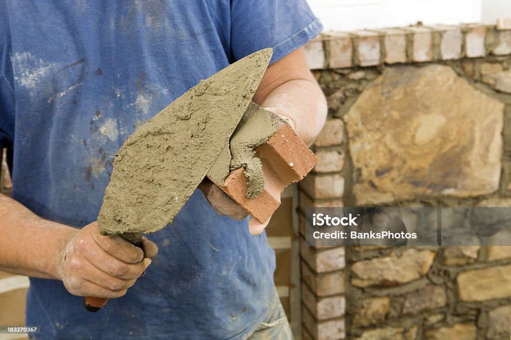 Stone Mason Buttering cemento mattoni con camino Surround per nuovi - Foto stock royalty-free di Muratore