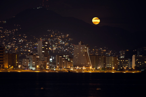 The moon rises over the resort of Acapulco, Mexico.