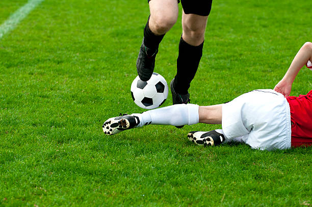 Two soccer players locked in close battle for control of ball on green soccer stadium against white studio background. Dribbling. Concept of sport event, motion, match, championship. Ad