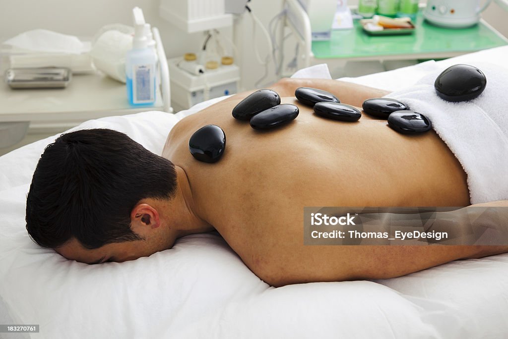 Man Having Lastone Therapy Man lies on his stomach with a Lastone arrangement on his back.  Horizontal shot Adult Stock Photo