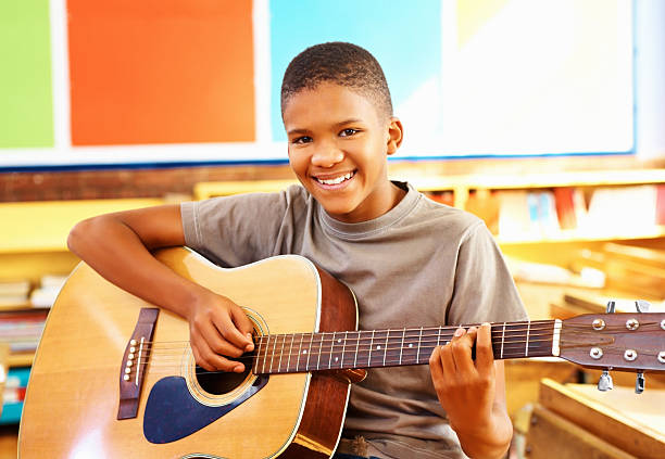 jeune garçon avec guitare acoustique en configuration salle de classe - guitar child music learning photos et images de collection