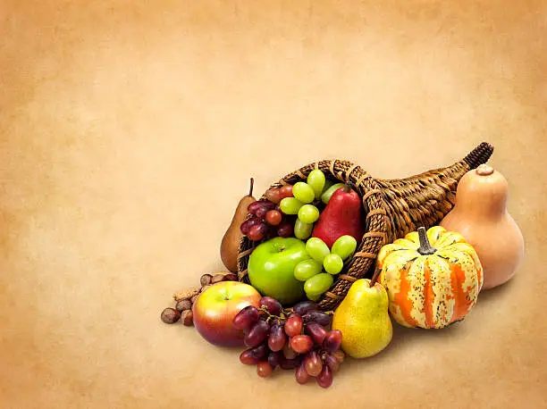 Thanksgiving cornucopia background with apples, grapes. pears, gourd, squash and nuts.