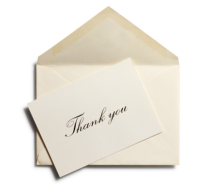 A thank you note at an angle on top of an envelope. Isolated on white with soft shadow.