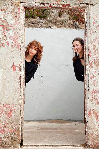 istock two young women peeking behind door 183271547