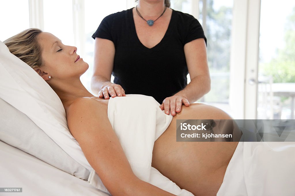 Pregnant Woman Receives Prenatal Massage and Reiki Energy Work A woman receives prenatal massage and Reiki from a midwife in preparation for childbirth. Pregnant Stock Photo