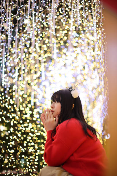istock Beautiful Asian young woman with a red sweater with Christmas tree light 1832728126