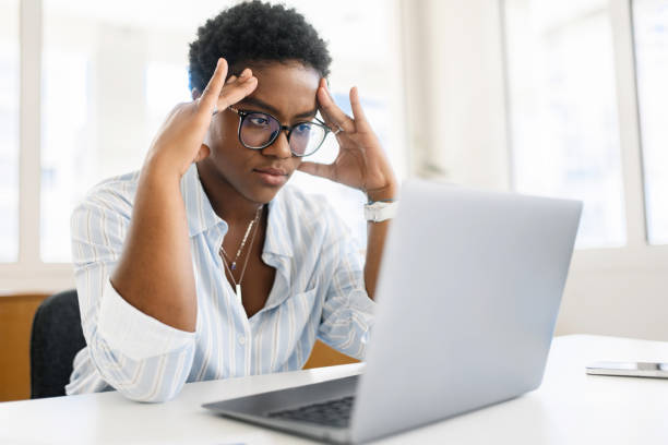 istock Tired young african-american female employee has problems with project, suffering from severe headache migraine. Weary freelancer woman overwhelmed with computer work 1832729745