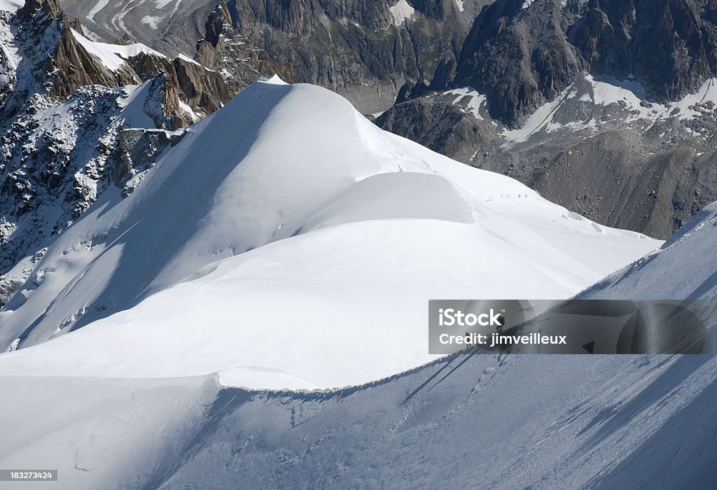 Hikers on a Narrow Glacier Ridge Near Mont Blanc "Two hikers connected by a rope descending a steep, snow covered glacier ridge in the mountains above Chamonix, France, and just below Mont Blanc." Adventure Stock Photo