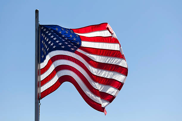 istock American Flag in the wind against clear blue sky (XXL) 183274144