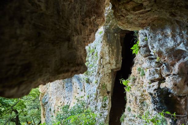 istock Dark cave view from inside with a lumen. Stalactites and stalagmites inside the stone grotto. Colorful stones in the cave. Lighting electricity beauty of the cave. 1832741932