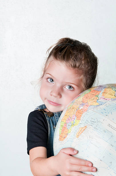 istock Little girl with a globe against white wall - II 183274428