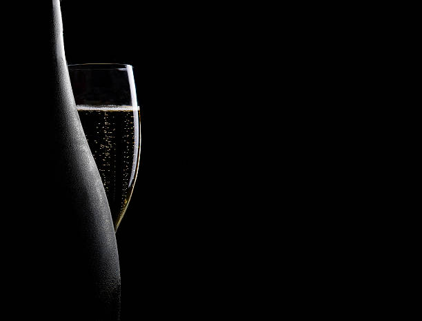 Glass and bottle of champagne Glass and bottle of champagne on a black background champagne bubbles stock pictures, royalty-free photos & images