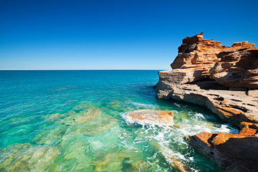 Bright red cliffs and turquoise ocean at Gantheaume Point, Broome, Western Australia.
