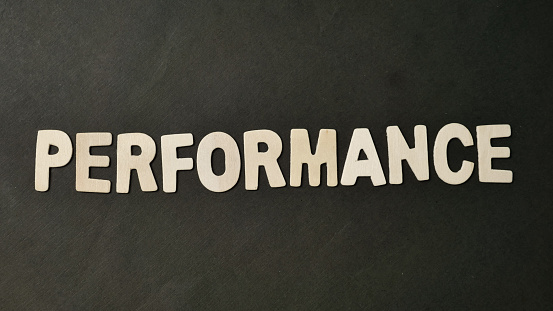 Performance text, written on wooden lettering, business term self improvement concept