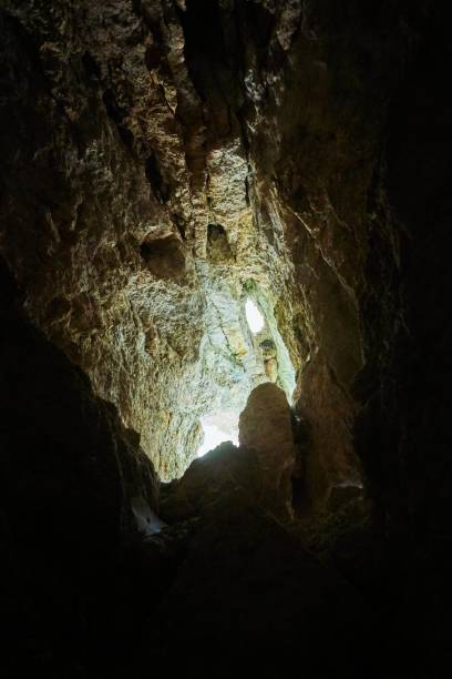 istock Dark cave view from inside with a lumen. Stalactites and stalagmites inside the stone grotto. Colorful stones in the cave. Lighting electricity beauty of the cave. 1832757892