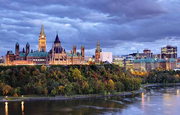 Parliament Hill  Ottawa, Canada Parliament Hill atop a dramatic hill overlooking the Ottawa River in Ottawa, Ontario in autumn. Parliament Hill is home to Canada's federal government and is the centrepiece of Ottawa’s downtown landscape. Ottawa is known for is high-tech business sector, vast array of museums and high standard of living. parliament building stock pictures, royalty-free photos & images