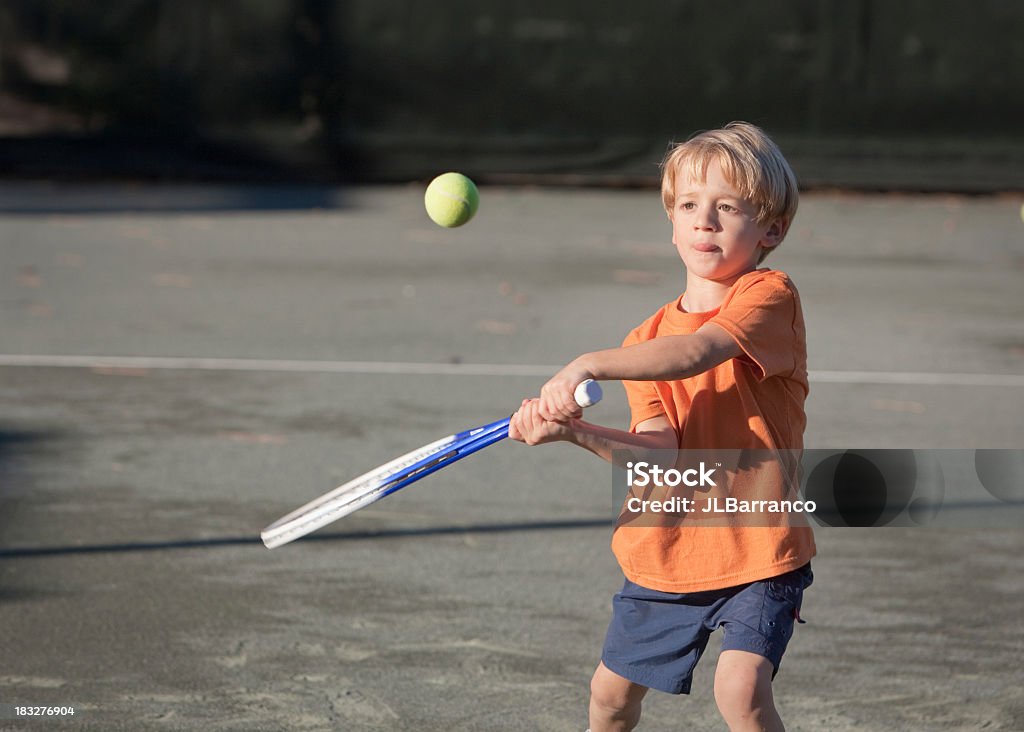 Young boy swinging a tennis racket at a tennis ball "Little boy with his eye on the tennis ball, determined to hit it.For similar and newly added tennis images, please visit my Tennis Anyone lightbox." Boys Stock Photo