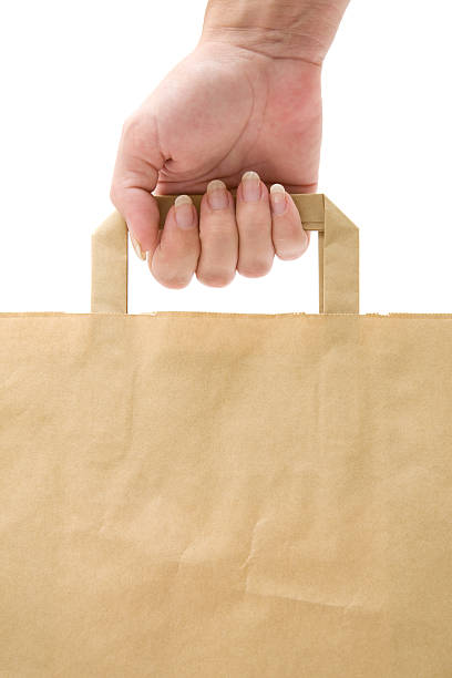 Carrying a brown paper shopping bag. White background.