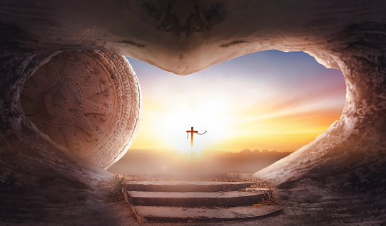 Easter concept: Empty tomb stone with cross on  sunrise background